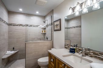 A modern bathroom with a walk-in shower, toilet, and vanity with a single sink.