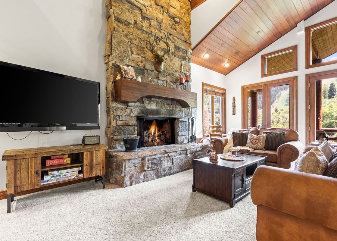 A cozy living room at Slopeside Deer Valley with a roaring fireplace, large TV, and plush seating.