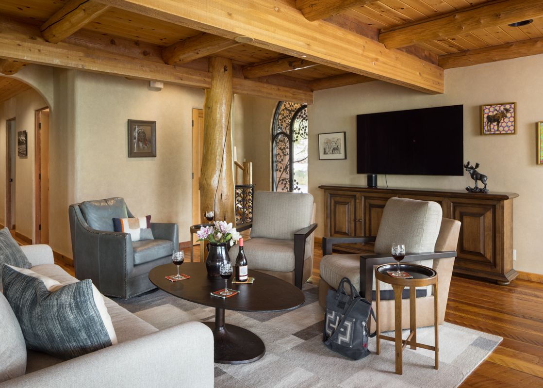 A cozy living room in Home on the Range with wood beams, comfortable seating, a flat-screen TV, and decorative artwork, featuring a natural and rustic design.
