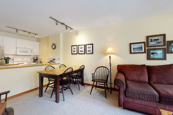 A welcoming interior shot of Aspens on Blackcomb Unit 206, featuring a modern kitchen, a dining area, and a comfortable living room with a couch.