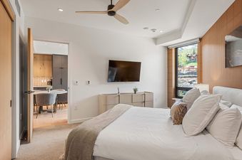 The master bedroom in Electric Pass Lodge 207 features a king-size bed with soft white bedding, a flat-screen TV, and a stunning view of the mountains through a large window.