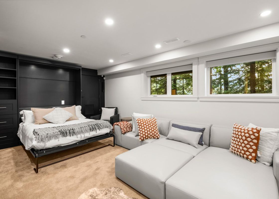 A modern basement living area featuring a comfortable sofa and a convenient pull-out bed, perfect for relaxation and accommodating guests.