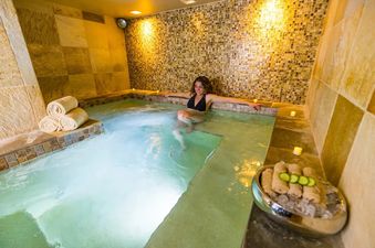 Indoor hot tub at Teton Mountain Lodge and Spa Lodge Two Queens with a woman relaxing in the water.