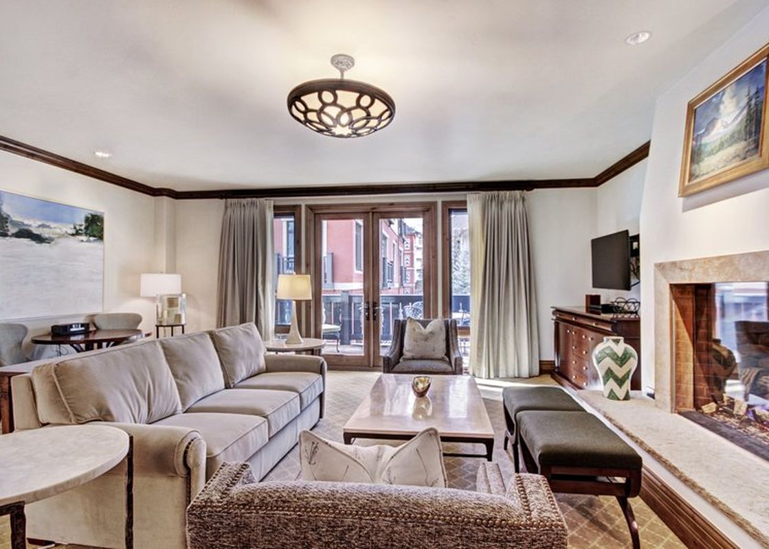 Cozy living area in the Arrabelle King Suite with a large stone fireplace, plush seating, and balcony access.