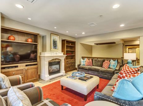 The living area of The Chateaux Four Bedroom Residence features a fireplace, a television, comfortable seating, and a decorative rug.