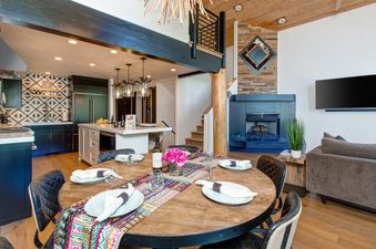 Dining area with a round table and a view into the modern kitchen and living space.