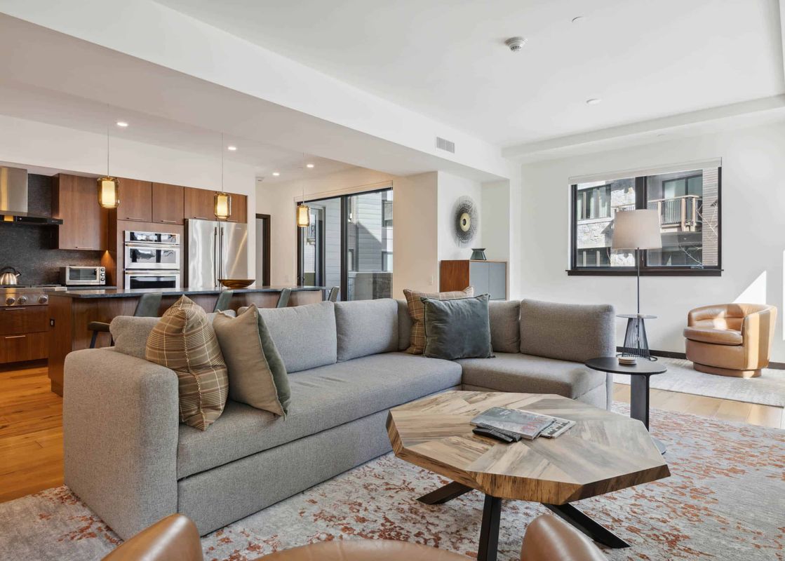 The living room of The Lion W302 features a large sectional sofa, a coffee table, a floor lamp, an armchair, and a rug.
