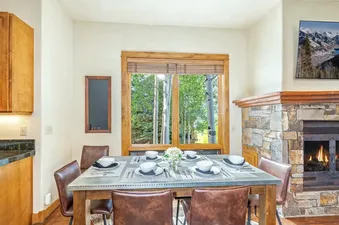 Dining table set for six next to a cozy stone fireplace inside Sunshine at the terraces.