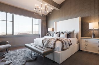 A luxurious bedroom at Silver Star 41DX featuring a king-sized bed with a white headboard, a tufted leather bench, and a large window with mountain views.
