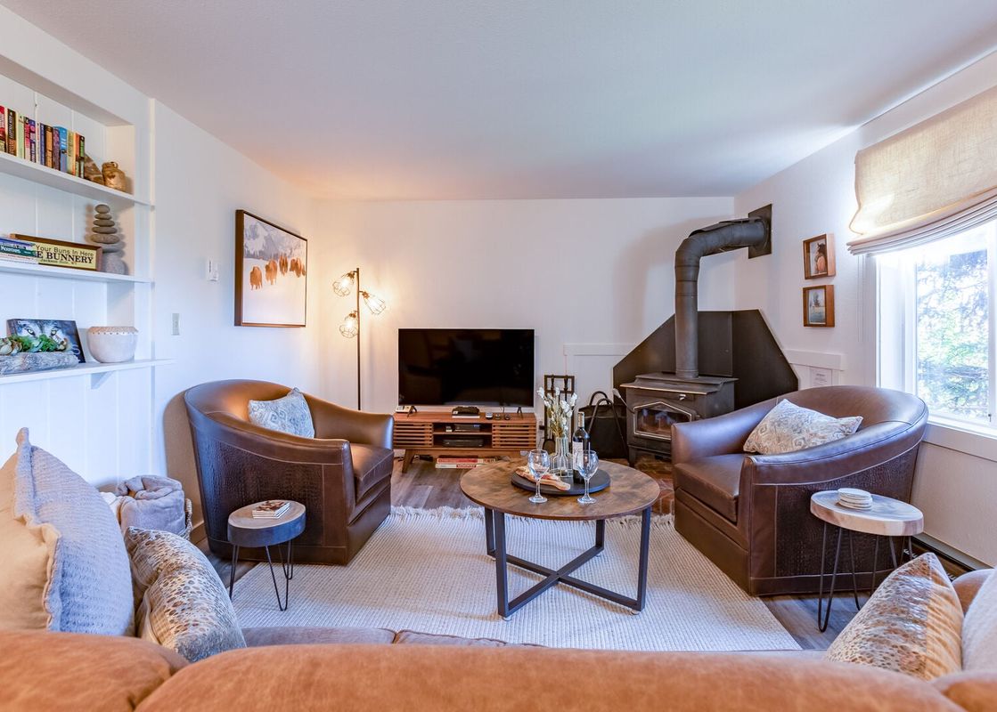 Cozy living room at Gros Ventre A10 with leather armchairs, a television, and a wood-burning stove.