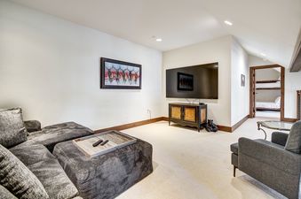 A cozy entertainment area with a large sectional sofa, a flat-screen TV above a rustic cabinet, and a painting of deer on the wall.