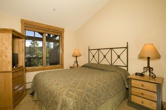 Master bedroom in the Mountain Thunder 2 Bedroom Condo featuring a queen bed and window with forest views.