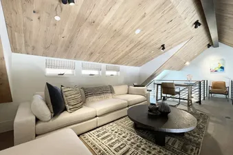 Loft House 101 at Transfer living room, with large comfy couch, coffee table, and rug, and a view to the upper floor of the house.