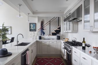 A modern white kitchen at The Nest in Jackson Hole with stainless steel appliances and a view of a staircase.