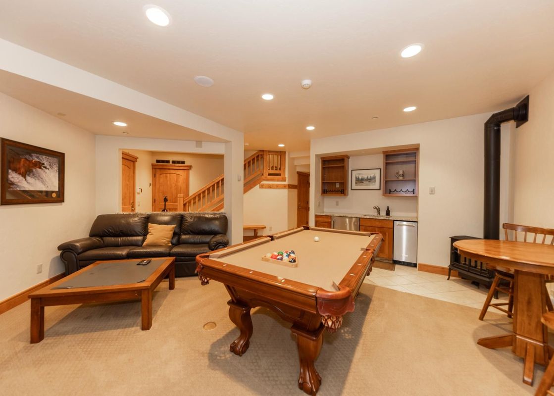 The Timber Trail Lodge features a well-lit recreation area with a pool table, comfortable seating, and a convenient wet bar, perfect for unwinding after a day of adventures.