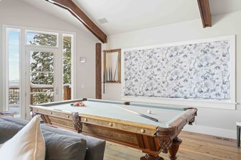 The inviting games room at 6977 Silver Lake Drive features a classic billiard table and views of the snowy landscape.
