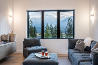 A living room with a large window overlooking a mountain range.