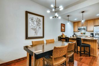 A modern kitchen with a dining table, chairs, and stainless steel appliances.