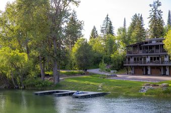 A serene lakeside retreat with a multi-story unit, private boat docks, and lush greenery under a clear sky.