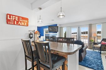 A cozy living area with a breakfast bar, fireplace, and scenic views of a snowy lake.