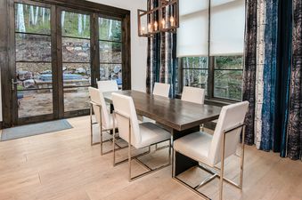 Dining area at Vail Chalet with a dark wooden table and white chairs.