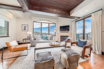 Lumiere Two Bedroom Residence features a bright and spacious living room with a large window showcasing stunning views of the mountains and a fireplace.