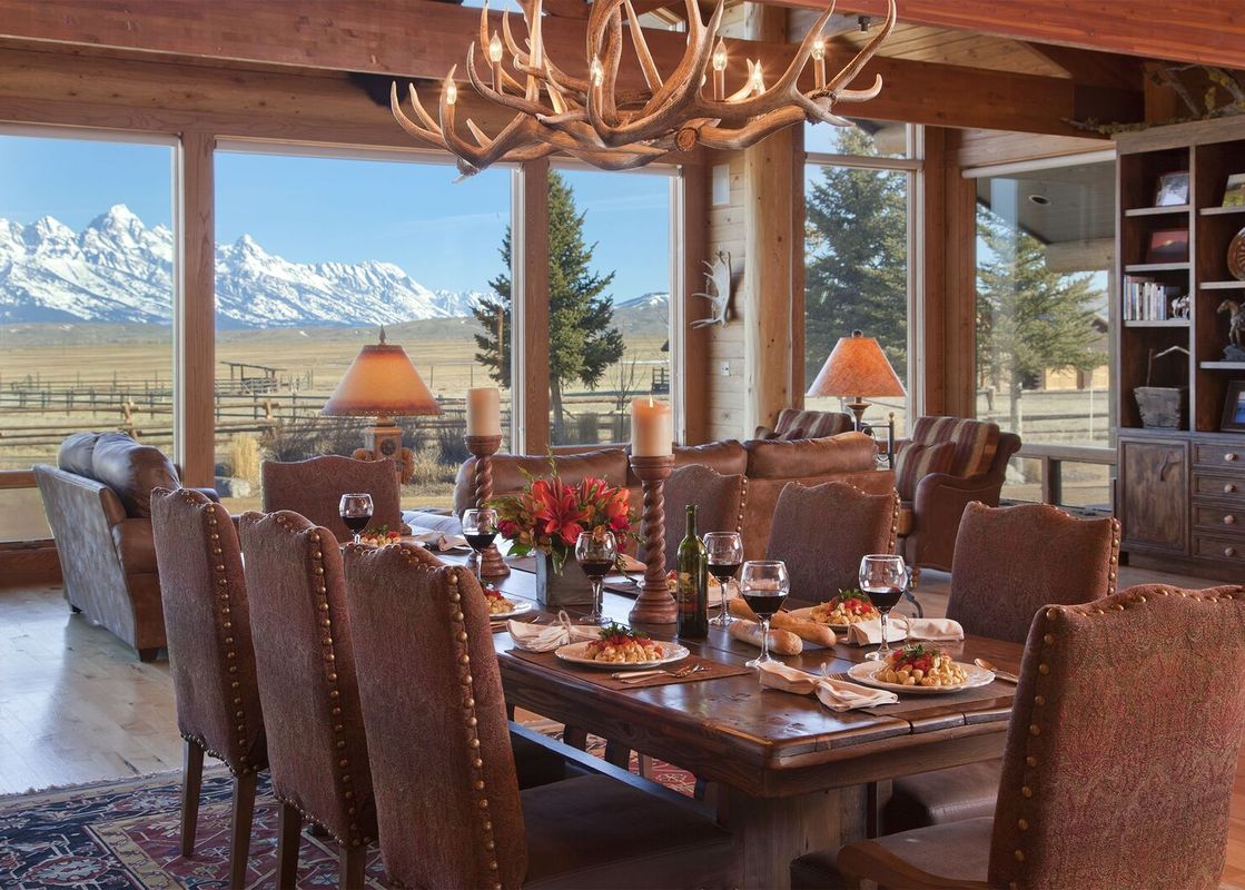 The dining room at Grand Teton Vista with a long wooden table set for a meal and a view of the mountains.