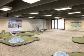 A spacious indoor mini-golf course with winter-themed obstacles, a ski resort mural, and a 'Beaver Run Resort at Breckenridge' wall art.