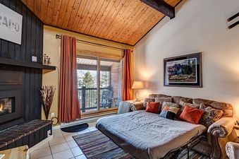 A living room with a fireplace, a pull-out couch, and a view of the mountains.