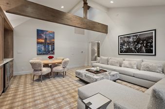 A spacious and inviting entertainment area at Casa de Gondola with a comfortable L-shaped sofa, a dining nook, a bar, and rustic wooden beams on the vaulted ceiling.