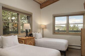Top of the Village Slope 408 bedroom with two twin beds, two lamps, and a window with a view of the trees.