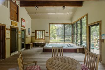 The hot tub room at Telluride Lodge Retreat features a large hot tub, comfortable seating, and expansive windows offering scenic views of the surrounding natural landscape.