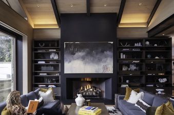The contemporary living room at Opus Estate features a fireplace, two comfortable sofas, and built-in bookshelves with decorative accents.