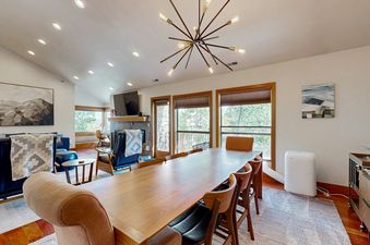 The dining area in Silver Cliff Village 205 has a large wooden table with chairs and a modern chandelier overhead.
