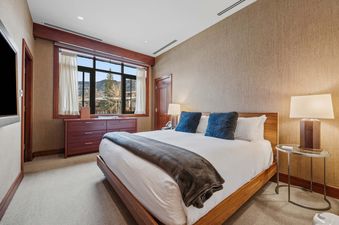 A cozy bedroom with a large bed, wooden furniture, and a window overlooking a mountainous landscape, capturing the inviting atmosphere of Solaris 2A South.