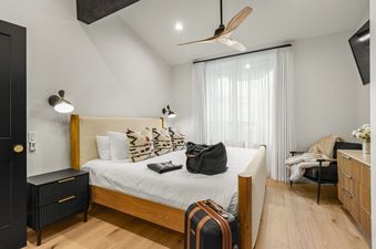 A luxurious king bedroom at Black Bear 404 featuring a king-sized bed with white linens, decorative pillows, and modern furnishings, including a sleek nightstand and a ceiling fan.