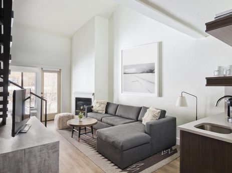 Modern and bright living area with a dark gray sectional sofa and a fireplace in the Gravity Haus JH Deluxe Loft.