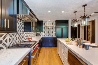 The modern kitchen in Abode in Snow Park features a spacious island, stainless steel appliances, and black and white patterned backsplash.