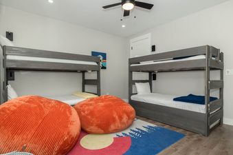A children's bunk room at Starview Chalet with two wooden bunk beds, colorful beanbag chairs, and a playful rug.