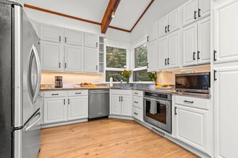 A modern kitchen with white cabinets, stainless steel appliances, and a vaulted ceiling in Alpine Retreat Jackson Hole.