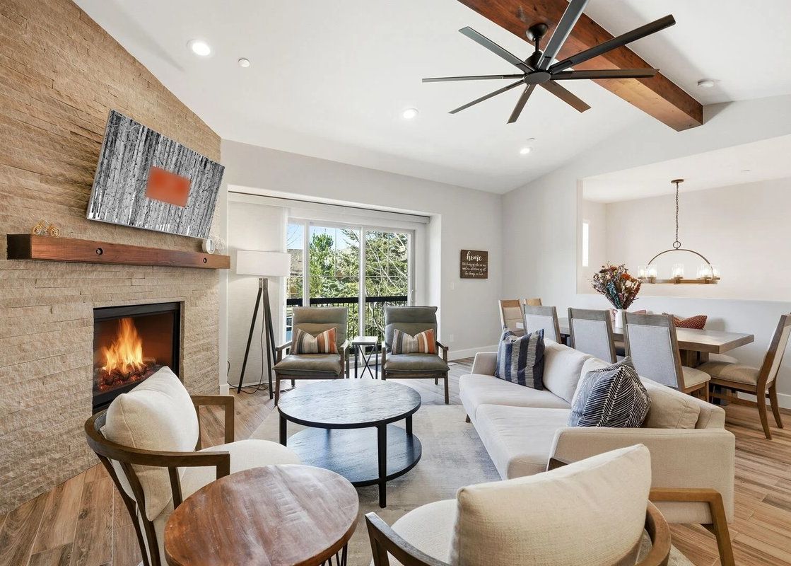 The contemporary living room of Snowline at Black Rock Ridge featuring a cozy stone fireplace and comfortable seating.