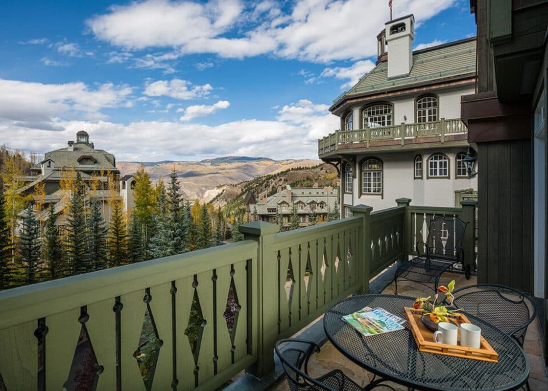 A private balcony at Chateau Beaver Creek Residence 406 with a patio table and chairs, offering scenic views of the resort buildings and autumnal mountains.