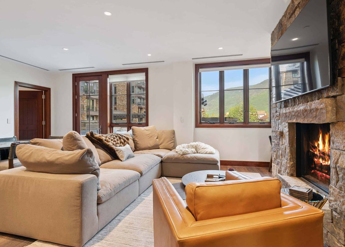 The living area at Solaris 3BS features a large sectional sofa, a fireplace, and views of the mountains through the windows.