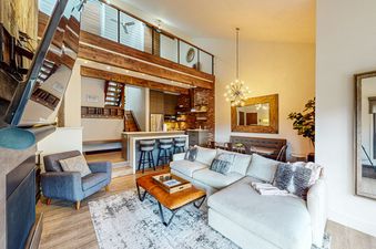 A living room with a large sectional sofa, a coffee table, a fireplace, and a large mirror on the wall.