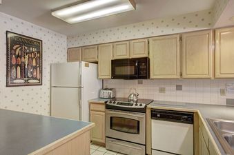A kitchen with white cabinets, stainless steel appliances, and a white refrigerator.