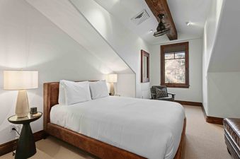 A serene bedroom at Silver Strike Lodge 705 featuring a large bed with white bedding, wooden accents, and a window overlooking a mountain landscape.