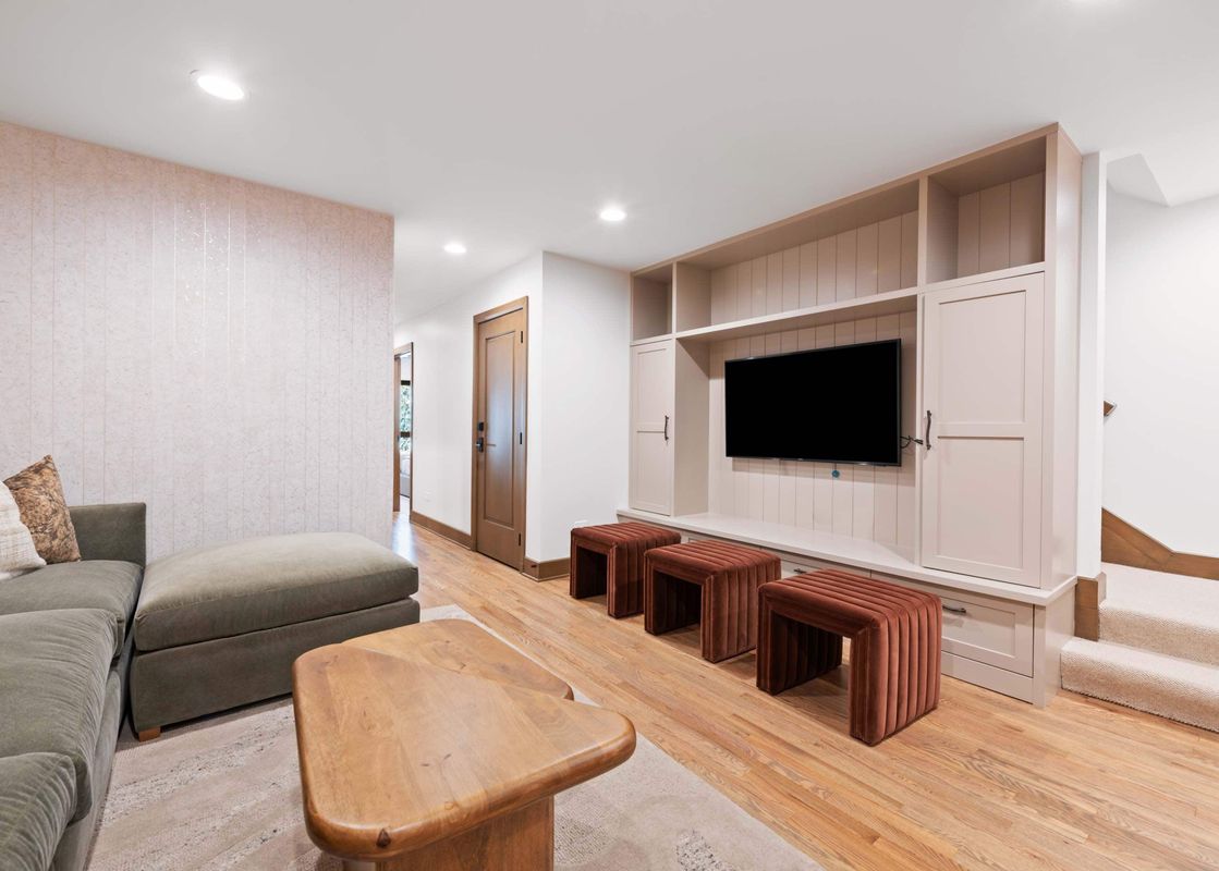A luxurious entertainment space at Village Hall 13, featuring a large screen TV, plush seating, and warm lighting.