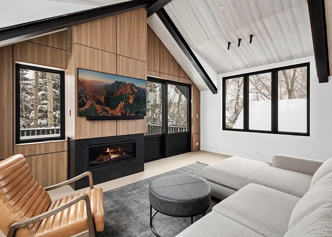 Modern cozy living room at Maison Cornet with a fireplace, TV, and snowy mountain views.