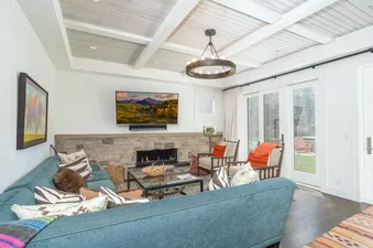 A cozy living room at East End Estate with a teal sectional, stone fireplace, and access to an outdoor patio.