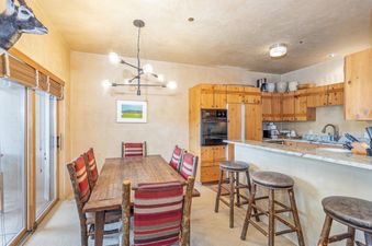 Dining area in Westermere 411 with a dining table, kitchen counter with stools, and a mounted animal head.